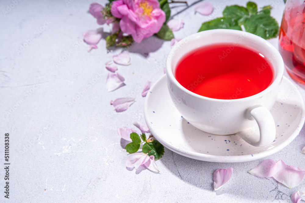 Rose buds tea, organic floral herbal hot tea drink with fresh rose flowers, in tea pot and cup, copy space Rose buds tea, organic floral herbal hot tea drink with fresh rose flowers, in tea pot and cup, copy space