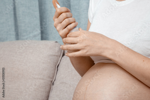 Close up of pregnant woman applying moisturizing cream on her belly. Concept of pregnancy and skin care. Pregnant woman putting cream on her belly to avoid stretch marks.