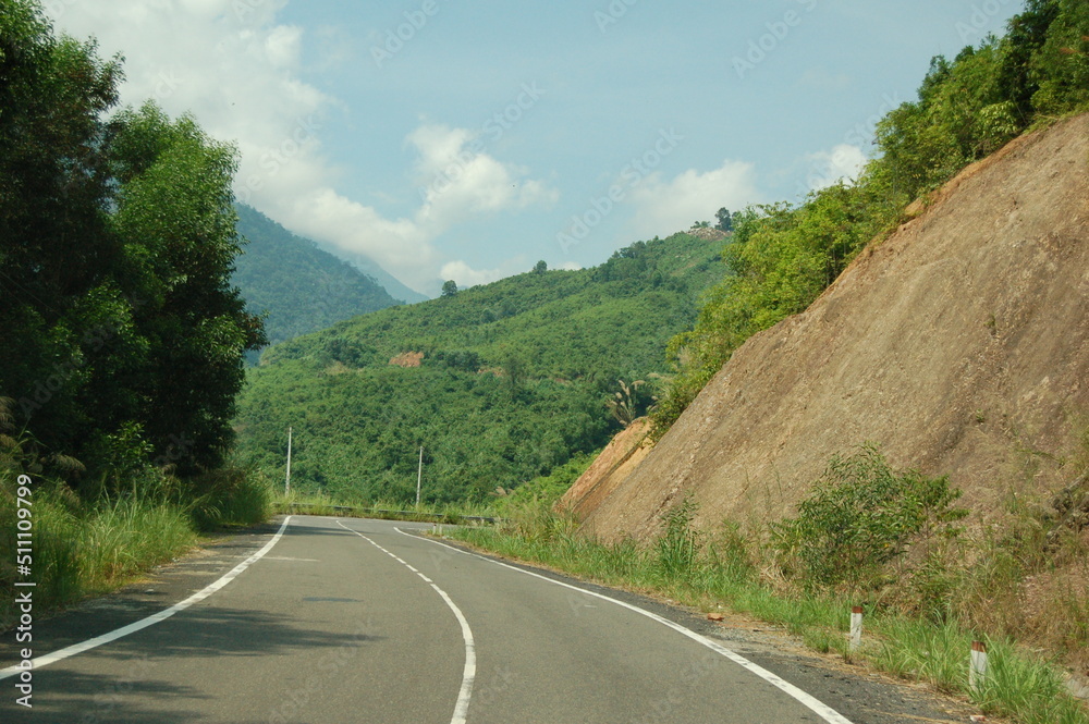 An asphalt road passes through a mountain pass among the jungle.