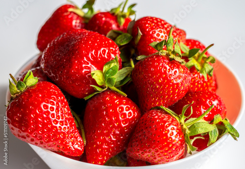 Ripe juicy strawberries in a white cup on a white background