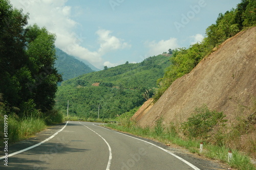 An asphalt road passes through a mountain pass among the jungle. © Houston