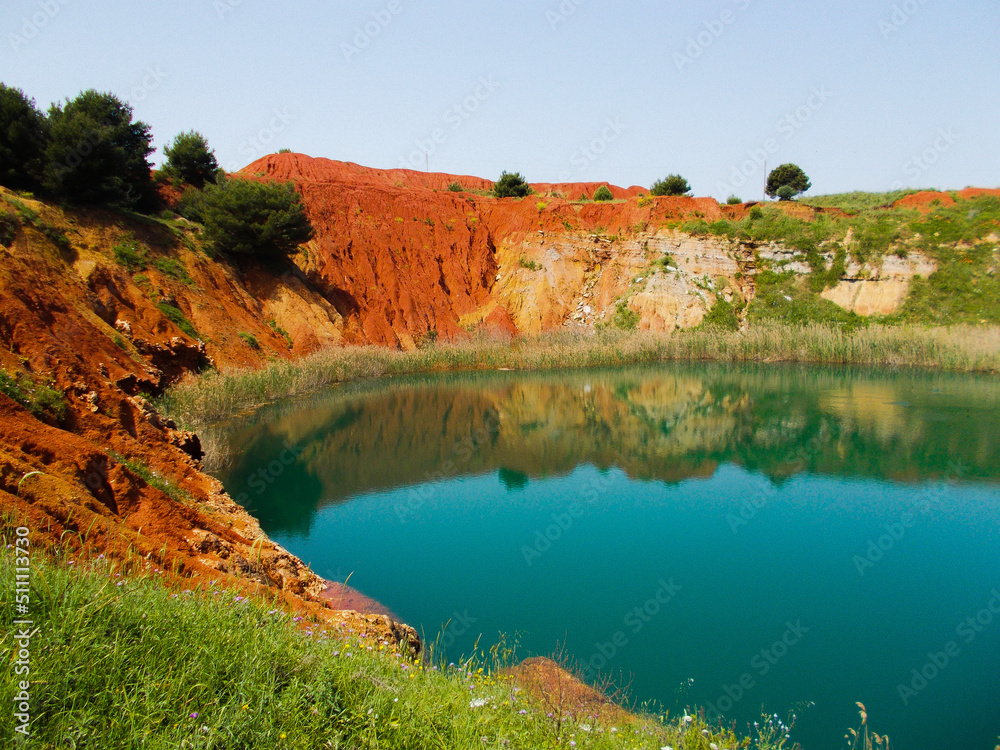 red sand and green water lake at bauxite cave in South Italy