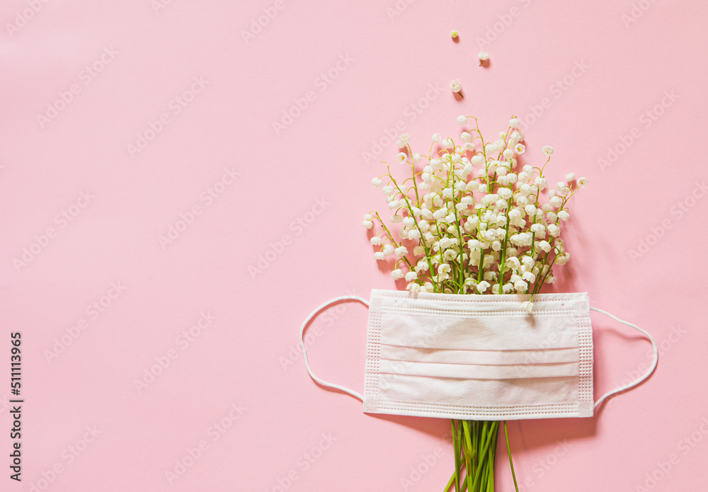 lilies of the valley and a medical mask on a pink background. flower allergy concept