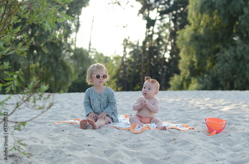 Babygirl and babyboy sitting on beach with glasses. Playing in sand. danger of sunstroke photo