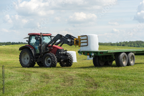 Farmer load hay bales to trailer.