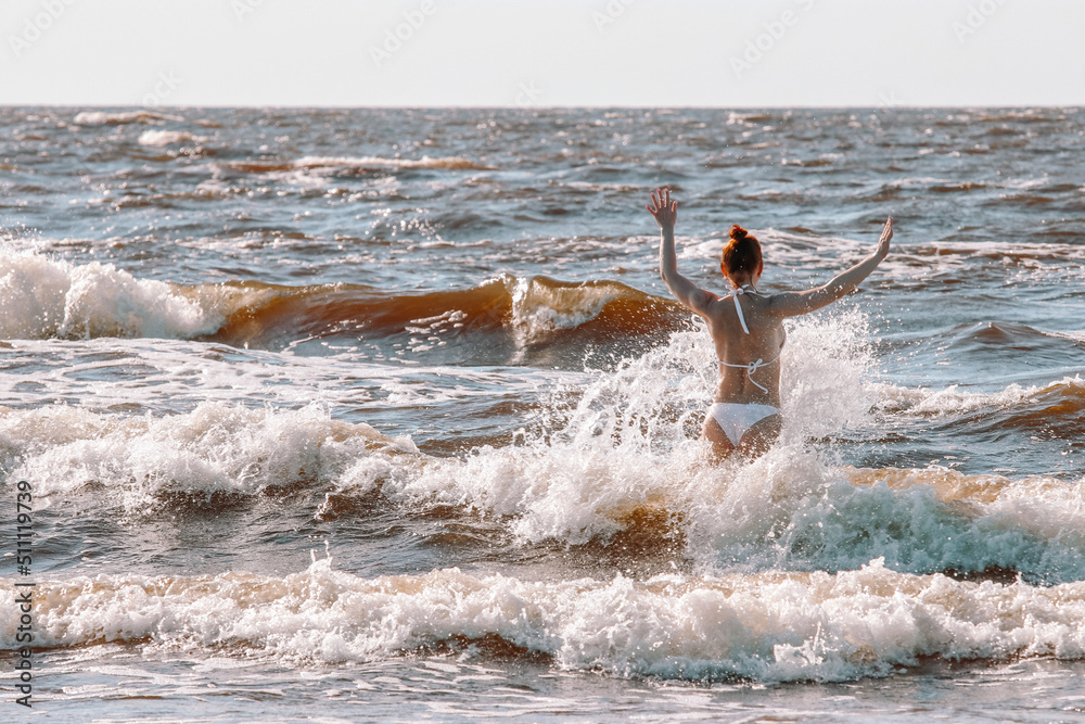 person on the beach,a girl in a white swimsuit, with a charming figure, swimming in the sea, a beautiful girl