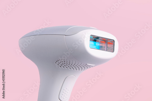 home modern laser epilator. Hair Remover offering Permanently Smooth Skin. Flash Epilator Laser on a pink background. Female blog concept. Photoepilator for home use. selective focus. close-up. photo