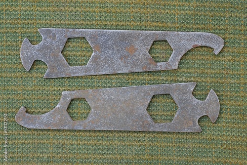 two old rusty iron bicycle tool lie on a green cloth