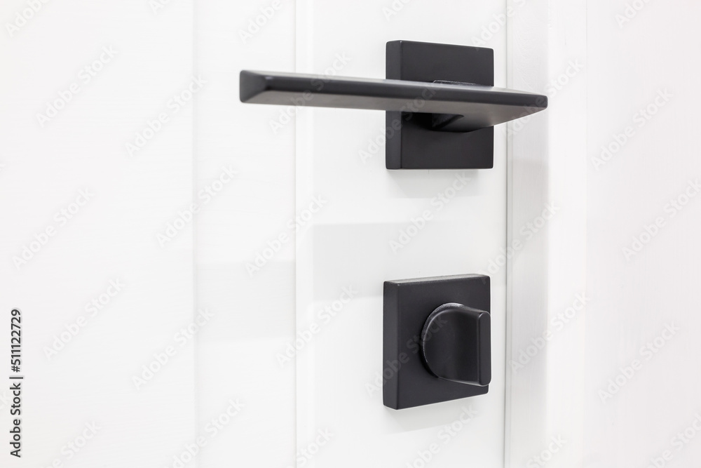 Modern black door handle on white wooden door in interior. Knob close-up elements. Door handle, fittings for interior design Modern black door handle on white wooden door in interior. Knob close-up elements. Door handle, fittings for interior design