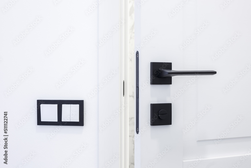 Modern black door handle on white wooden door in interior. Knob close-up elements. Door handle, fittings for interior design Modern black door handle on white wooden door in interior. Knob close-up elements. Door handle, fittings for interior design