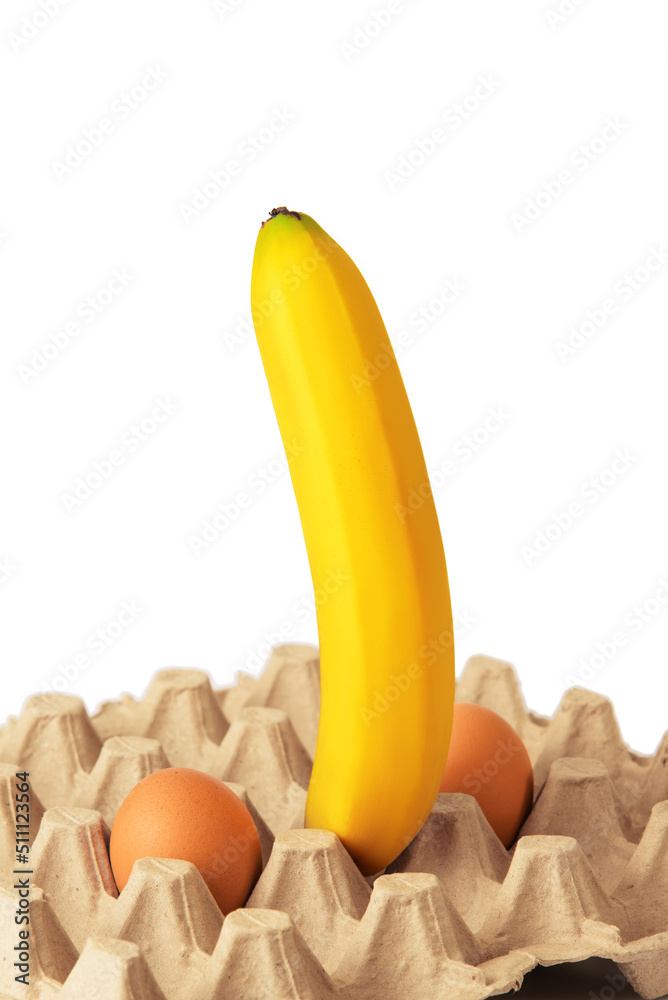 Big ripe banana and two chicken eggs in egg carton on white background. Sexy concept.