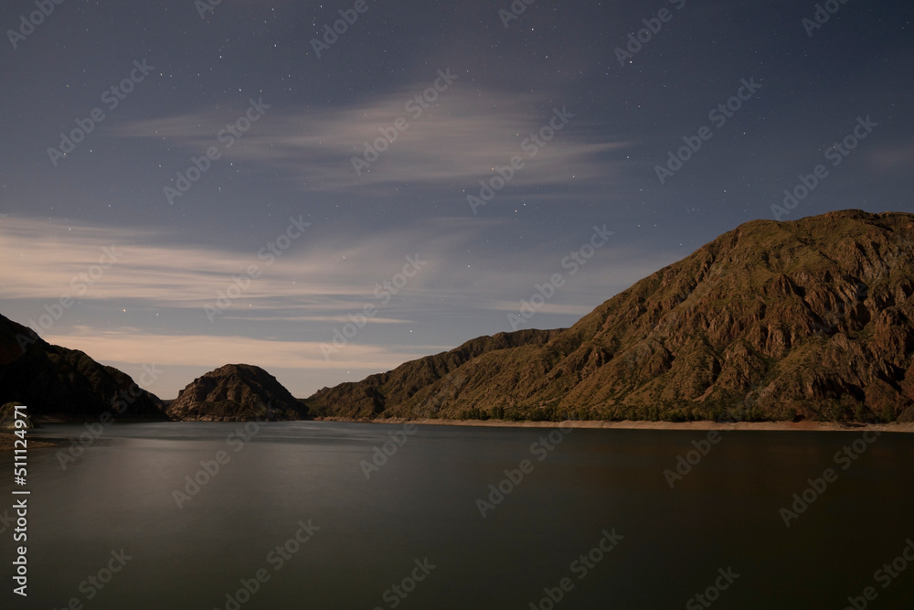 Night shot. View of the placid lake, stars and mountains. Beautiful blurred water effect and color generated by long exposure.	