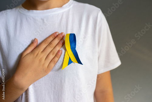 Yellow and blue ribbon on white t-shirt weared by young woman. Ukrainian national flag colors.