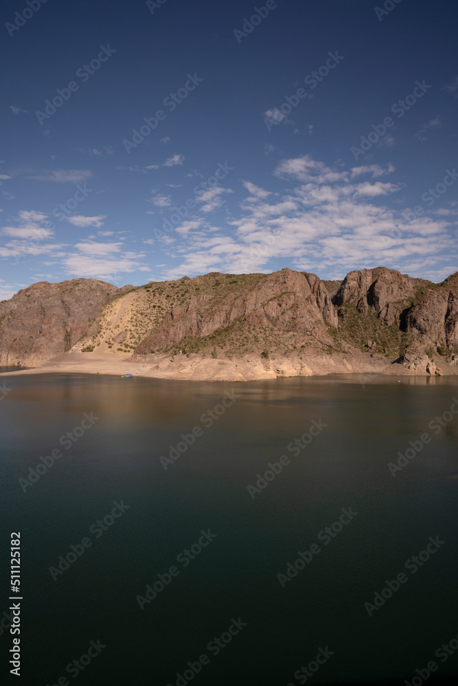 View of the lake and rocky hills in the desert under a deep blue sky.