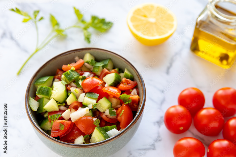 Tomato and cucumber salad. Fresh vegetable cut in cubes with lemon juice mixed in bowl. Tomato and cucumber salad. Fresh vegetable cut in cubes with lemon juice mixed in bowl.