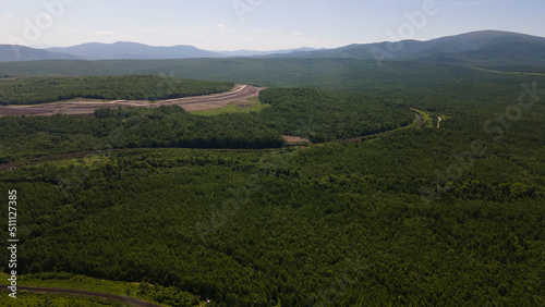 Aerial View of the Railway in taiga, mountains near to dirt road with tracks in sunny summer afternoon