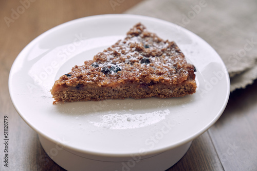 A delicious piece of lemongrass with blueberries and cranberries  without milk and eggs on flaxseed flour. Part of the pie is on a white plate on the table. The concept of healthy eating