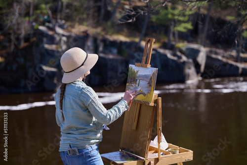 Girl artist paints nature on canvas with oil paints