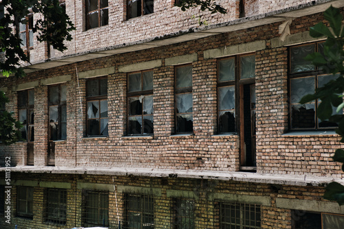 The wall of an old abandoned brick building with broken windows. Facade of destroyed building.