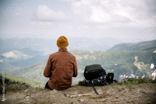 A tourist sits on the edge of a mountain peak. Foggy mountains on the background. Landscape photography