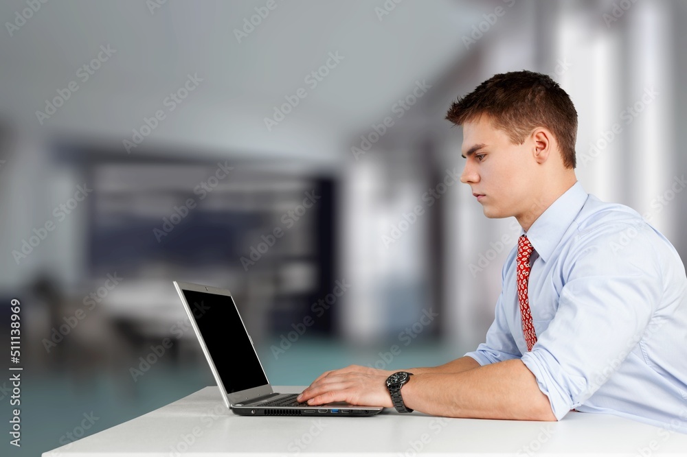 Remote job concept. Happy young man sitting at workdesk, using modern laptop, typing on computer keyboard and smiling, looking for job online,
