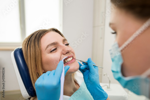 The dentist checks the teeth of a young patient sitting in a dental chair.