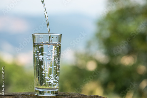 A glass of water a background of mountains, closeup, copy space, blurred background