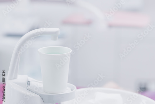 A glass with a mouthwash next to the dentist's chair