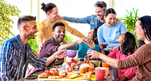 multiethnic group of friends sitting at table in a bar restaurant having brunch making funny faces. diverse people celerating sweet breakfast together enjoying happy holiday. lifestyle and joy concept photo