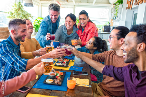 multiethnic large group of friends sitting at table in a bar restaurant having brunch. diverse people celerating salty breakfast together enjoying happy holiday. lifestyle and joy concept