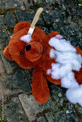 teddy bear lying on the floor destroyed with a knife