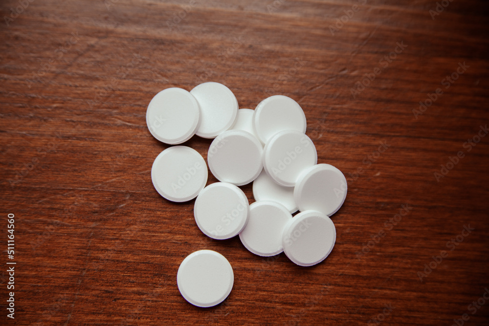 Tablets are scattered on a dark wooden table. Background for pharmacy, antibiotics, vitamins. drug pills
