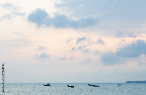 Pink and blue sunset on the coast of the South China Sea. Silhouettes of fishing boats near the horizon. Vietnam.