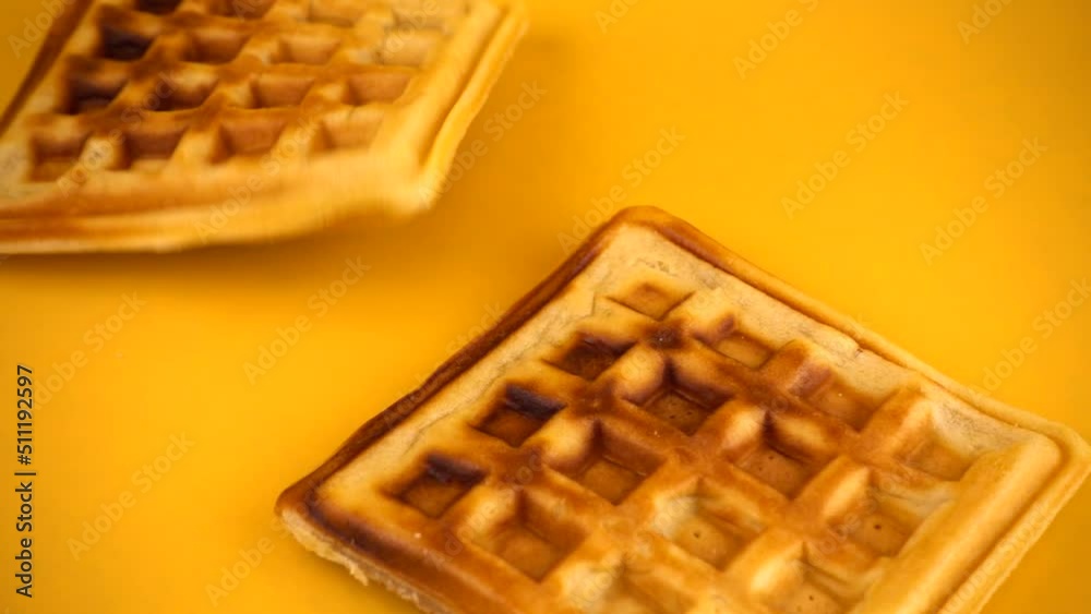 Belgian waffles are falling down on a yellow background. Slow motion. Belgian waffles are falling down on a yellow background. Slow motion.
