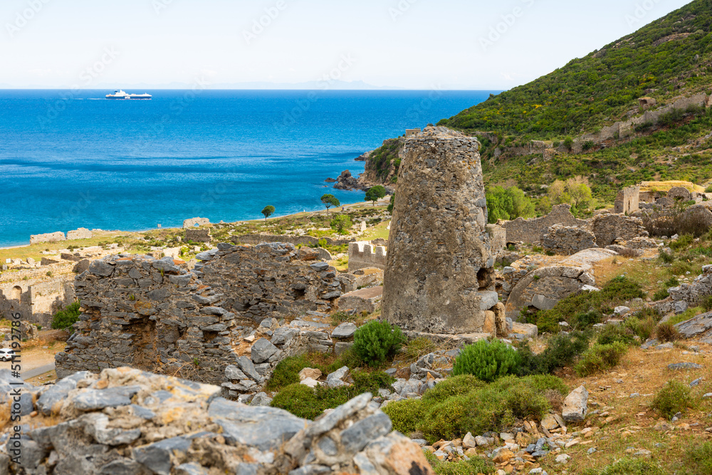 Scenic view of stone ruins of necropolis in ancient city of Anemurium on hillside on background of blue water of Mediterranean Sea on sunny spring day, Mersin province. Archaeological sites of Turkey