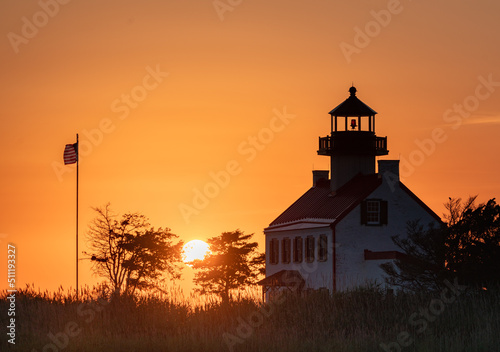 East Point Lighthouse in front of a fiery, setting Sun. 