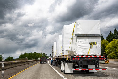 Bild auf Leinwand Powerful big rig semi truck tractor transporting heavy duty equipment on flatbed