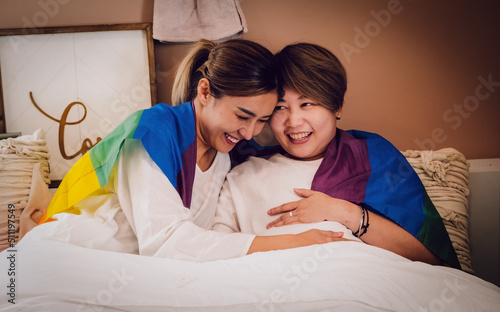 A young lesbian couple lying in a relaxed atmosphere in the bed is happy about positive pregnancy test. Love, pregnancy, lgbt, relationship. Togertherness concept. photo