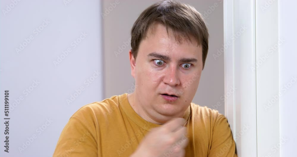 Portrait of young man who looks at what is happening with horror, eyes wide open, he shakes his head in disbelief and makes the sign of the cross praying to God, front view Portrait of young man who looks at what is happening with horror, eyes wide open, he shakes his head in disbelief and makes the sign of the cross praying to God, front view