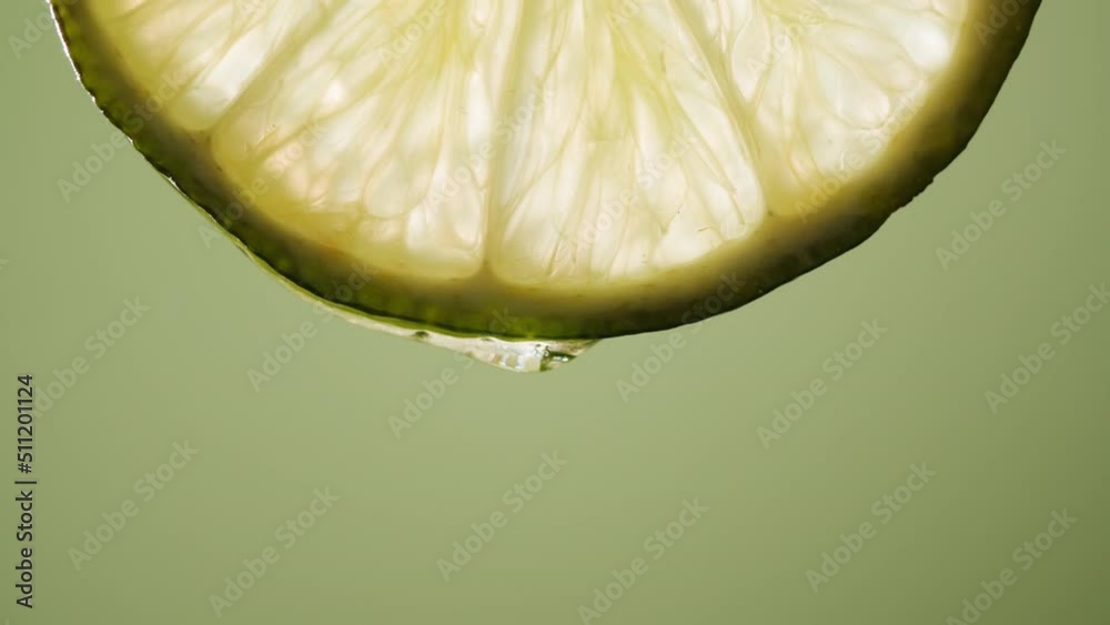 Juicy lime slice on green background. Citrus fruit close-up texture, healthy sweet food. Summer refreshment concept.