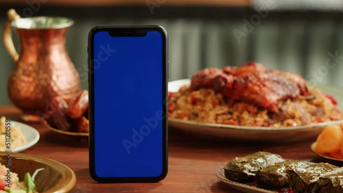 Kabsa, hummus, dolma, maqluba, tabbouleh close-up, smartphone with blue chroma key screen, middle eastern national traditional food. Muslim family dinner, Ramadan, iftar. Arabian cuisine. photo