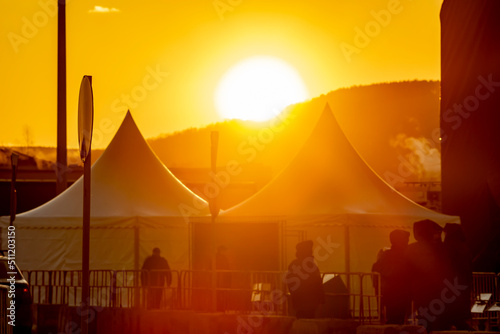 orange  soft  defocused image of a city tent camp for police officers with silhouettes of military people against the background of a bright  large sunset sun