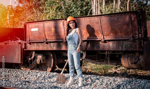 Portrait beautiful woman coal worker showed working near railway station with orange helmet and shoveling coal