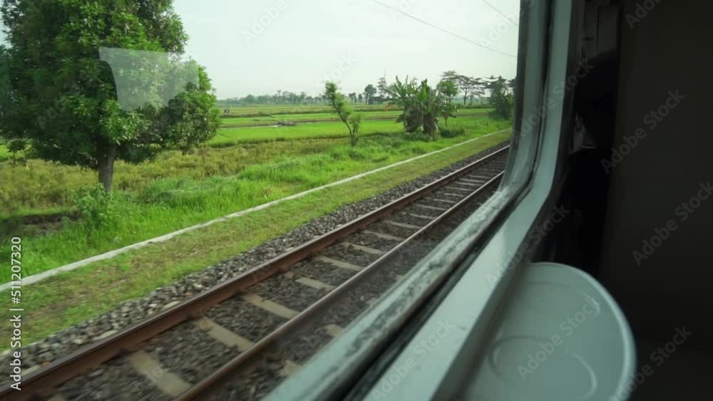 Ride the train sitting by the window looking at the view of the tracks and rice fields outside the window the train is speeding towards its destination Ride the train sitting by the window looking at the view of the tracks and rice fields outside the window the train is speeding towards its destination