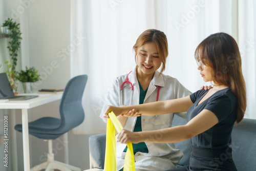 Fotobehang Asian woman physiotherapist oversees the patient’s stretching with elastic tape