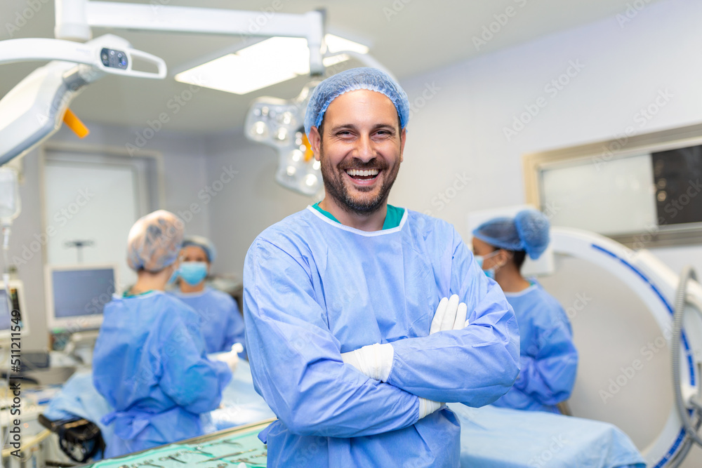 Obraz premium Portrait of male surgeon in operation theater looking at camera. Doctor in scrubs and medical mask in modern hospital operating room.