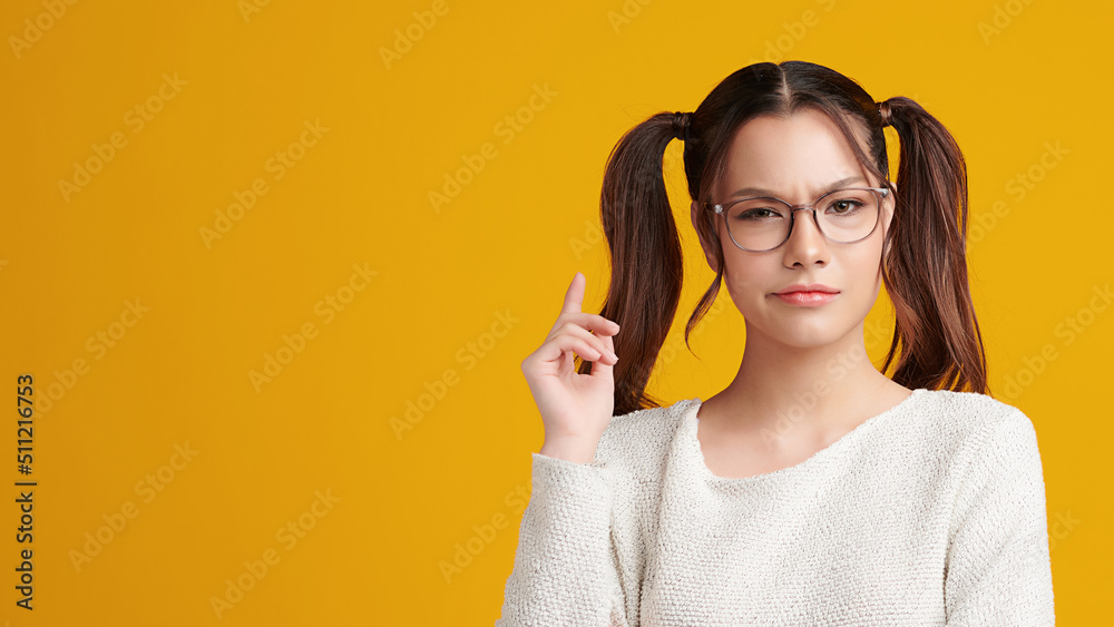 Curious Asian girl is thinking and standing on yellow background with curious face, blank copy space for your advertising content. Curious Asian girl is thinking and standing on yellow background with curious face, blank copy space for your advertising content.