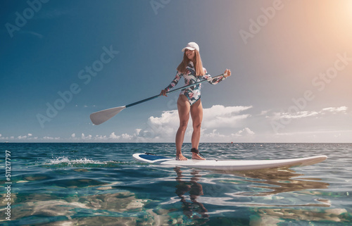 Healthy happy fit woman in bikini relaxing on a sup surfboard, floating on the clear turquoise sea water. Recreational Sports. Stand Up Paddle boarding. Summer fun, holidays travel. Active lifestyle