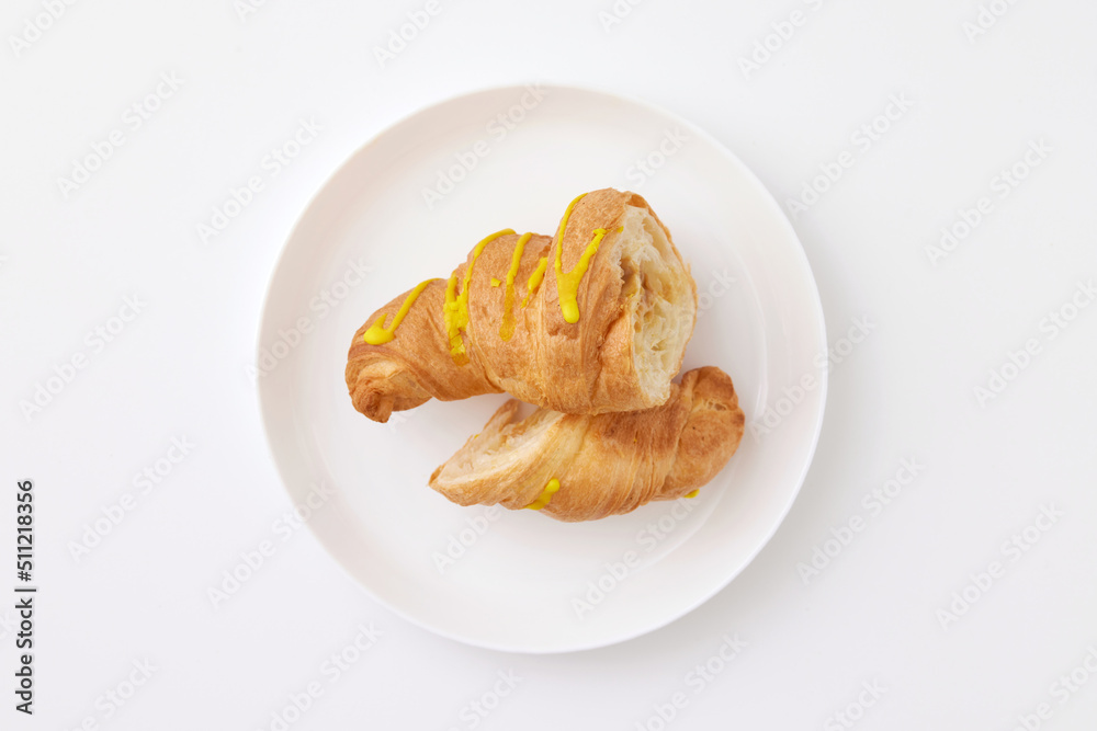 Top view image of sliced french croissant with glaze and jam filling served at plate isolated at white background.