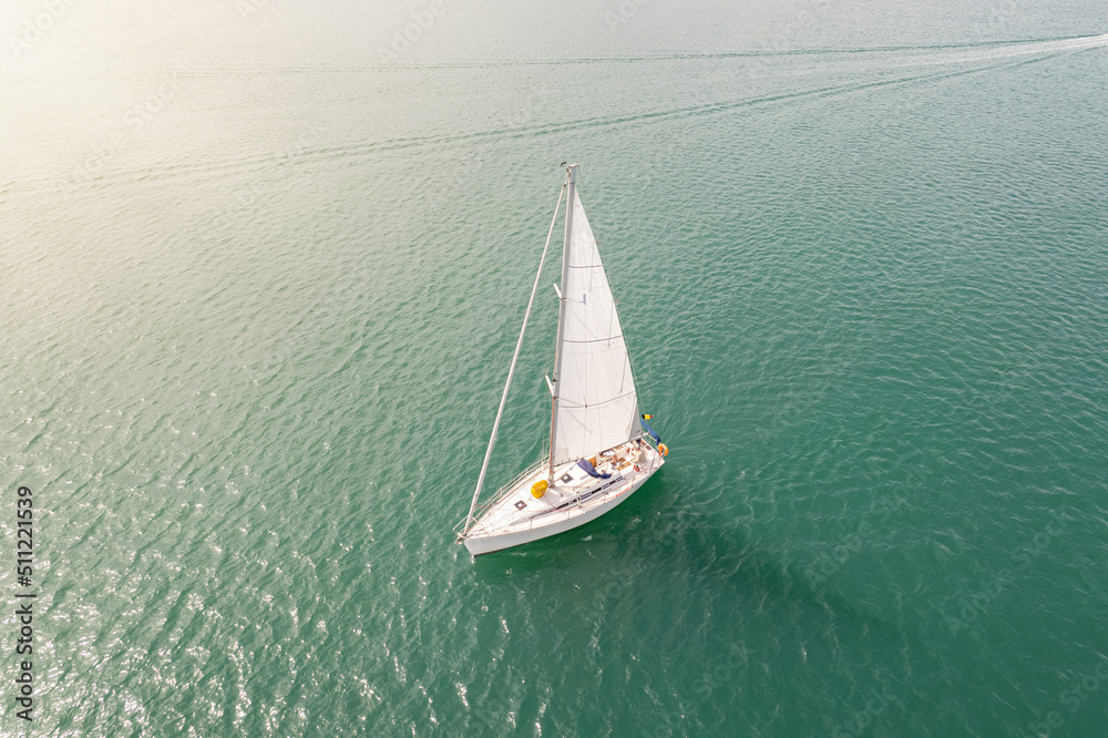 Fototapeta premium Aerial view of sailing yacht with white sail